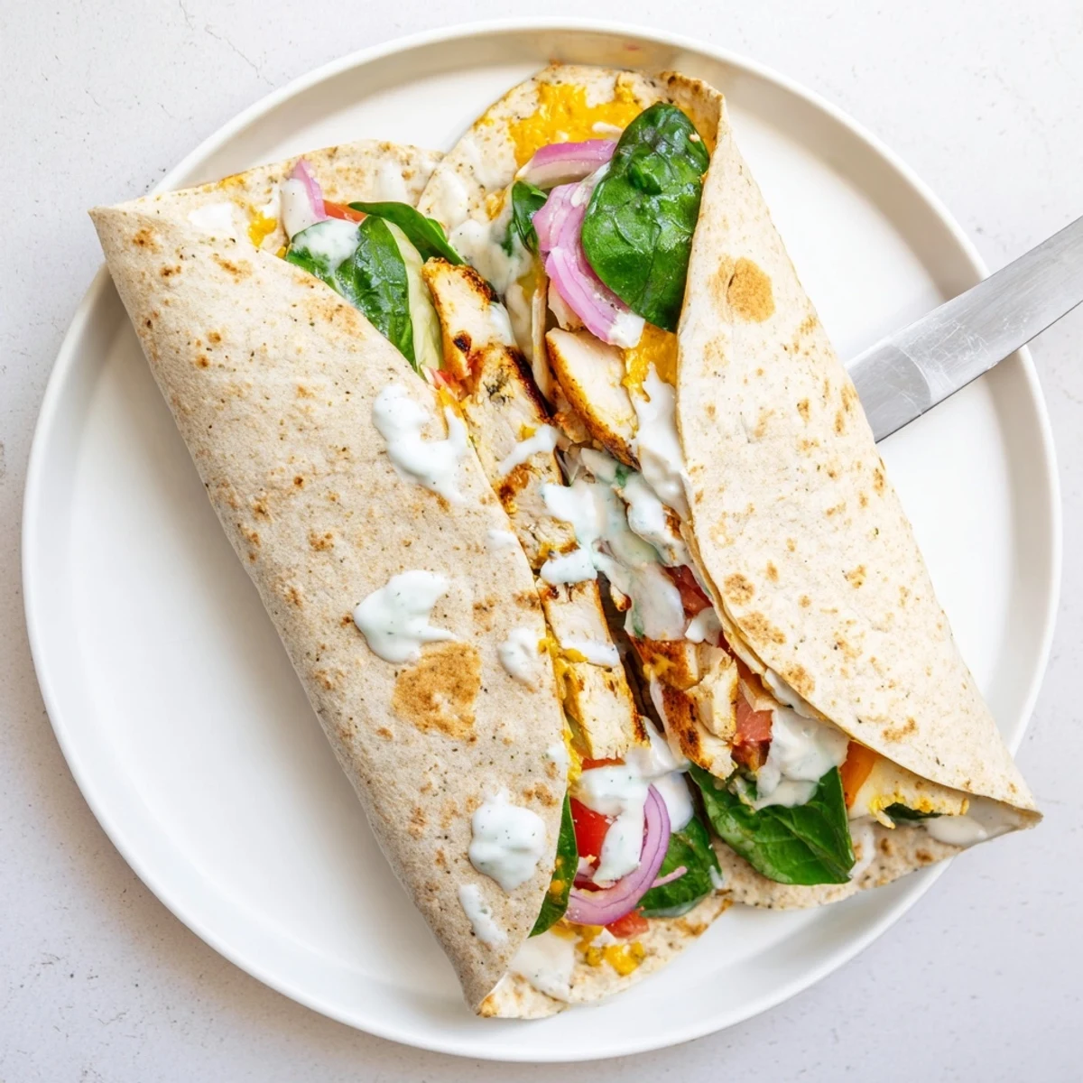 Sliced low carb cheesy garlic chicken wraps revealing tender spiced chicken and crisp veggies