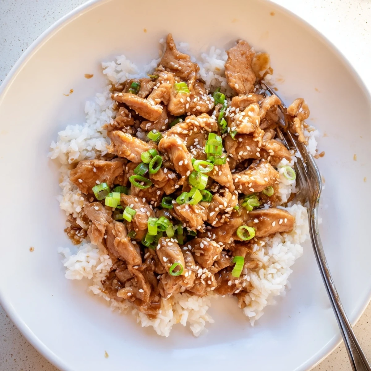 Shredded chicken pieces swimming in thick sweet savory teriyaki glaze in slow cooker