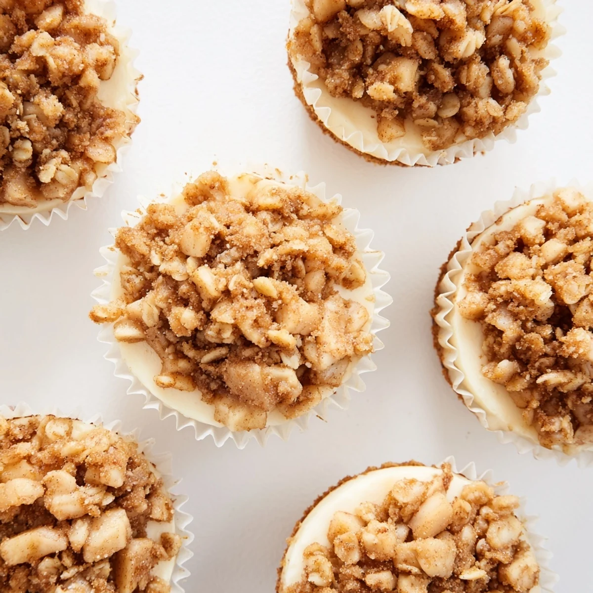 Creamy individual cheesecakes with buttery oat apple topping on graham cracker crust