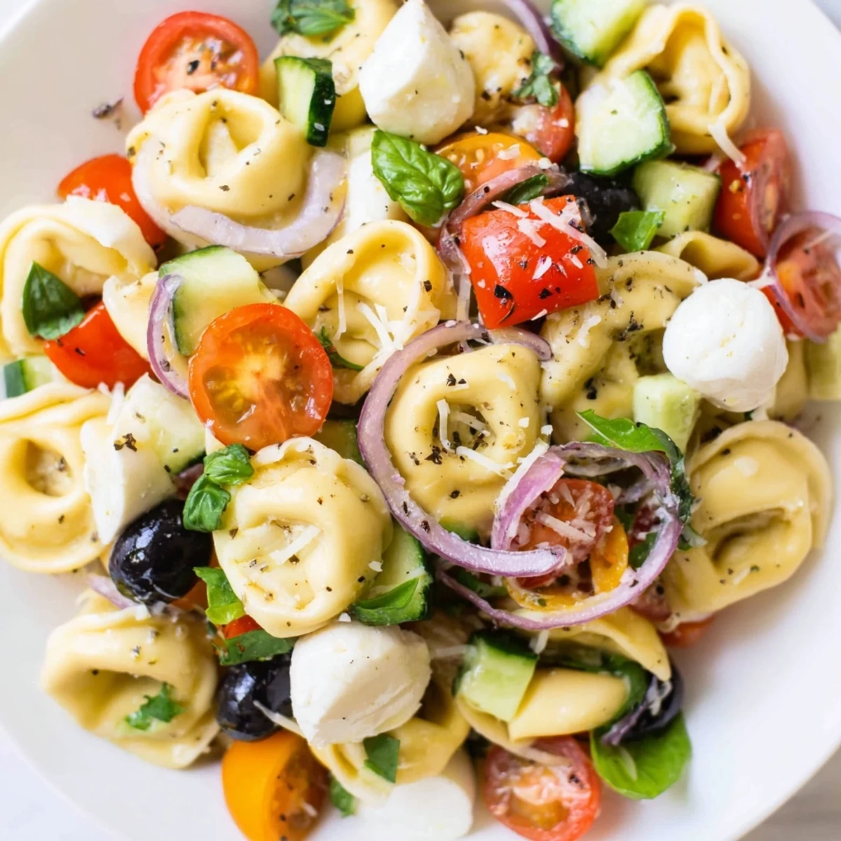 Colorful tortellini salad with cherry tomatoes, cucumber, and mozzarella in Italian dressing