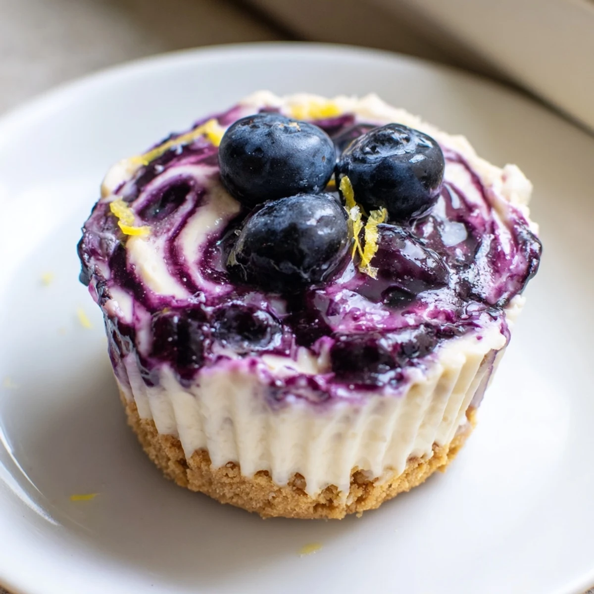 Chilled mini lemon blueberry cheesecakes garnished with fresh berries and bright lemon zest