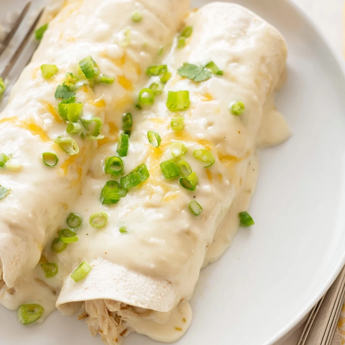 Creamy White Chicken Enchiladas baked golden, bubbling cheese, garnished with cilantro  