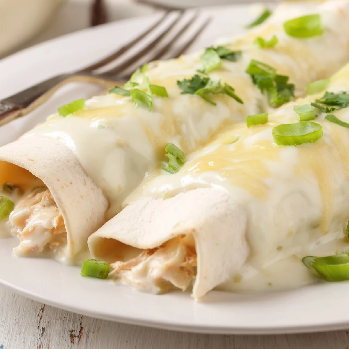Warm Creamy White Chicken Enchiladas sliced on plate, served with Spanish rice