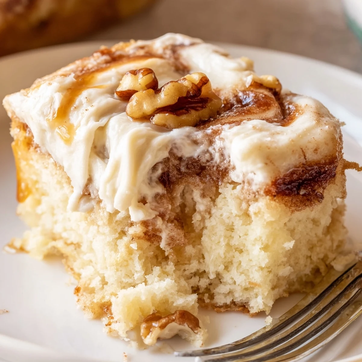 A warm Cinnamon Roll Poke Cake slice steaming beside vanilla ice cream