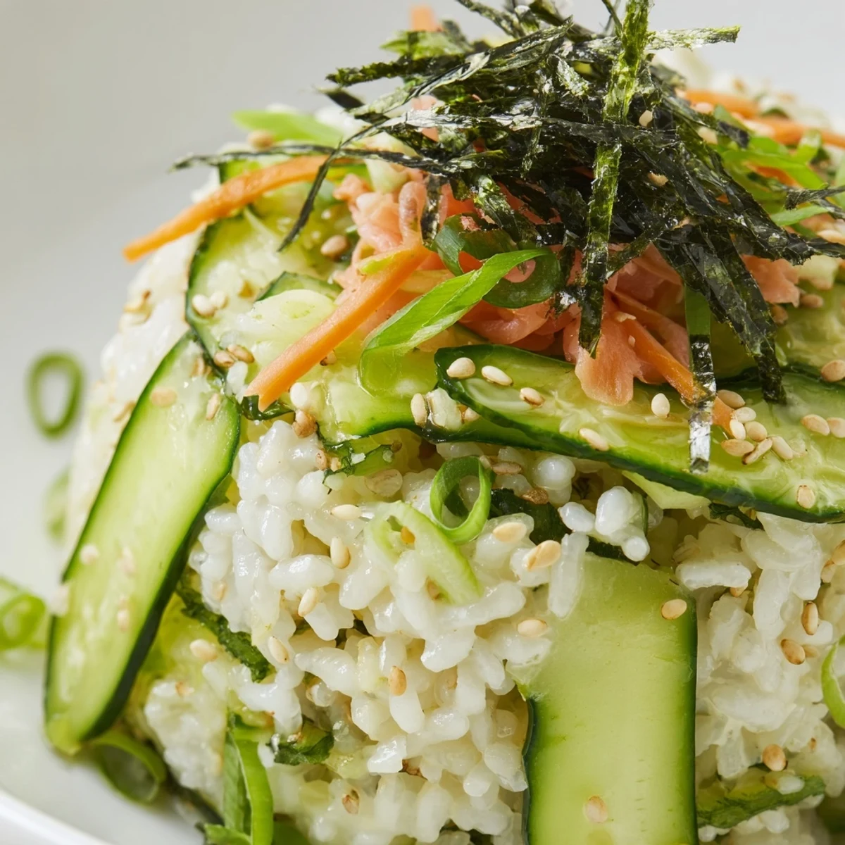 Sushi Cucumber Salad piled in bowls, avocado slices and pickled ginger