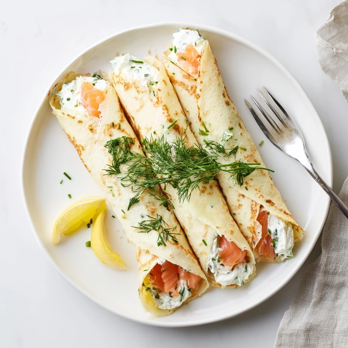 Elegant brunch plate featuring smoked salmon crepes recipe topped with chives and sour cream