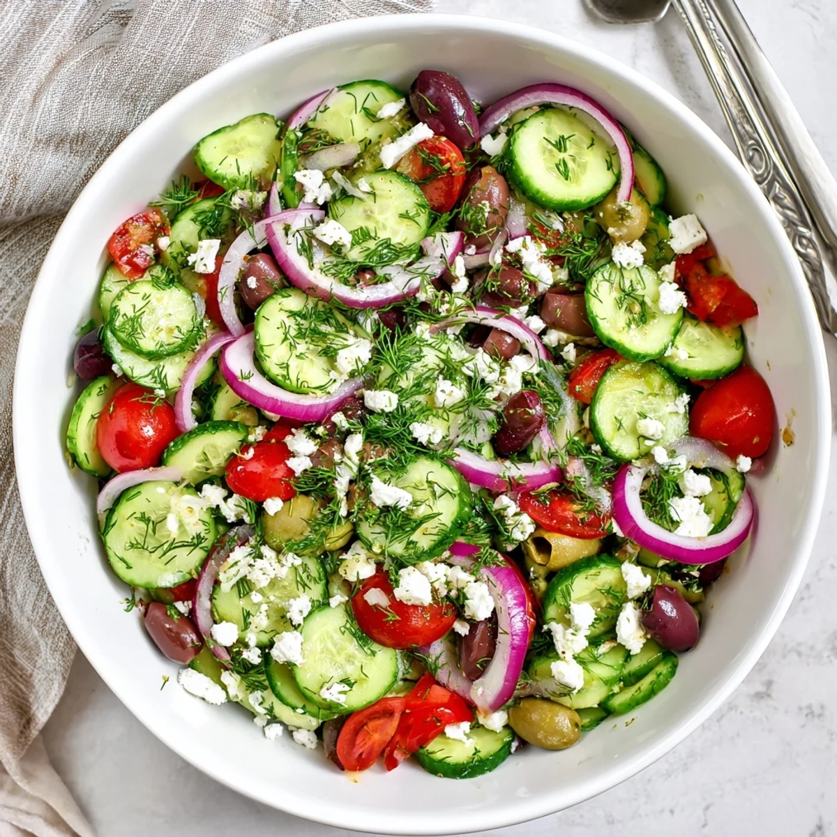 Vibrant Mediterranean cucumber salad recipe displaying layered cucumbers, cherry tomatoes, red onion, and Kalamata olives.