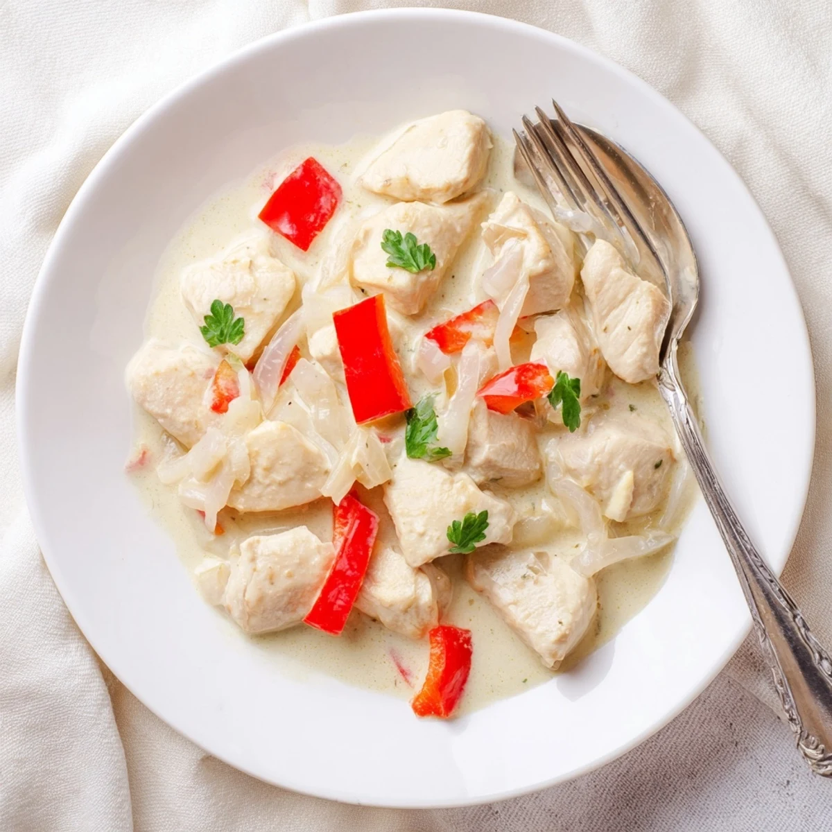 Tender chicken breast cubes swimming in aromatic coconut curry sauce with diced red peppers and green onions
