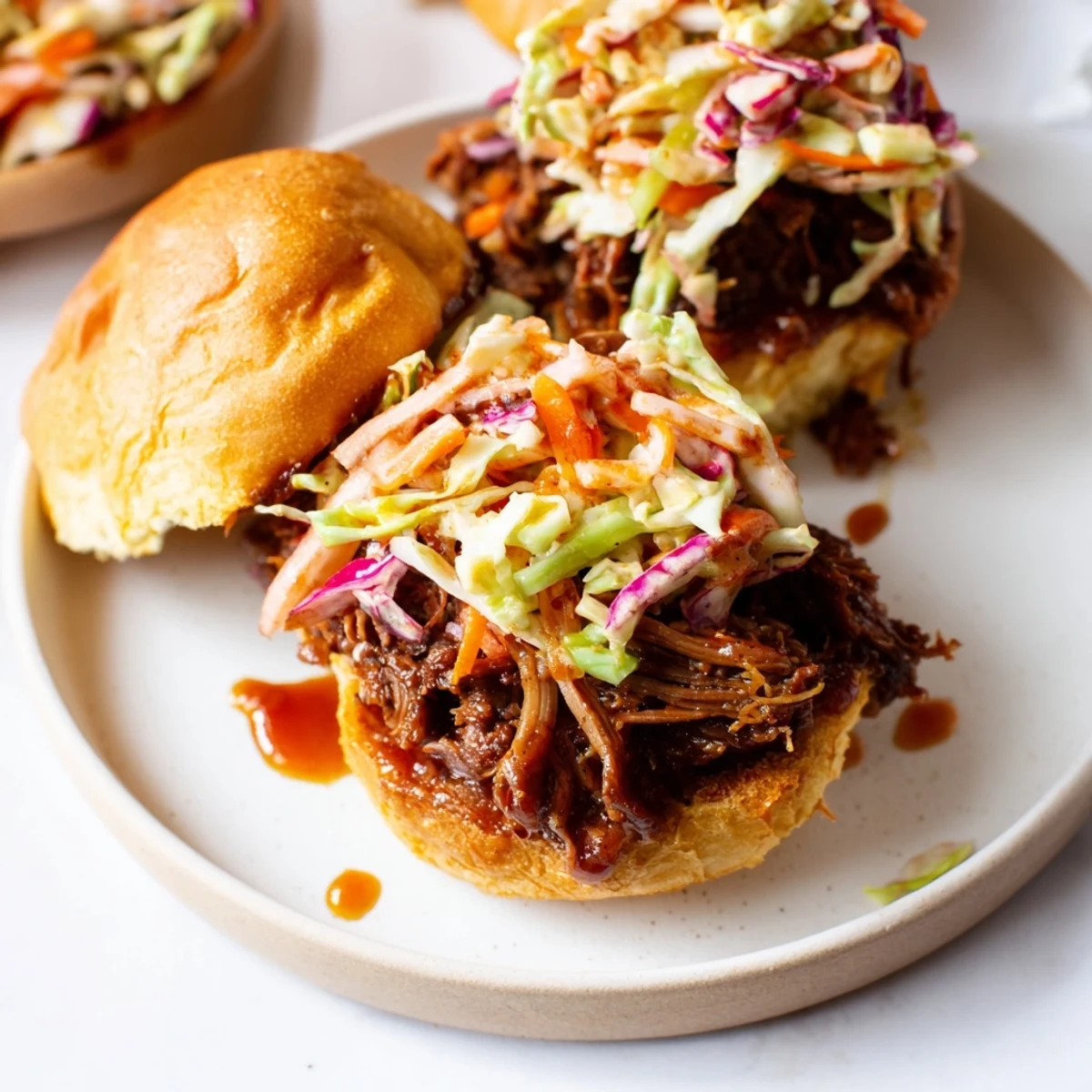 Smoky BBQ pulled beef sandwiches topped with crisp colorful coleslaw and served on soft brioche