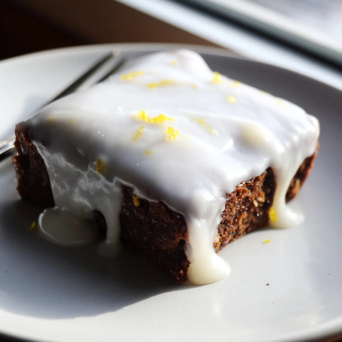 Golden lemon zest buttery brownies drizzled with white glaze and fresh zest garnish on a serving plate