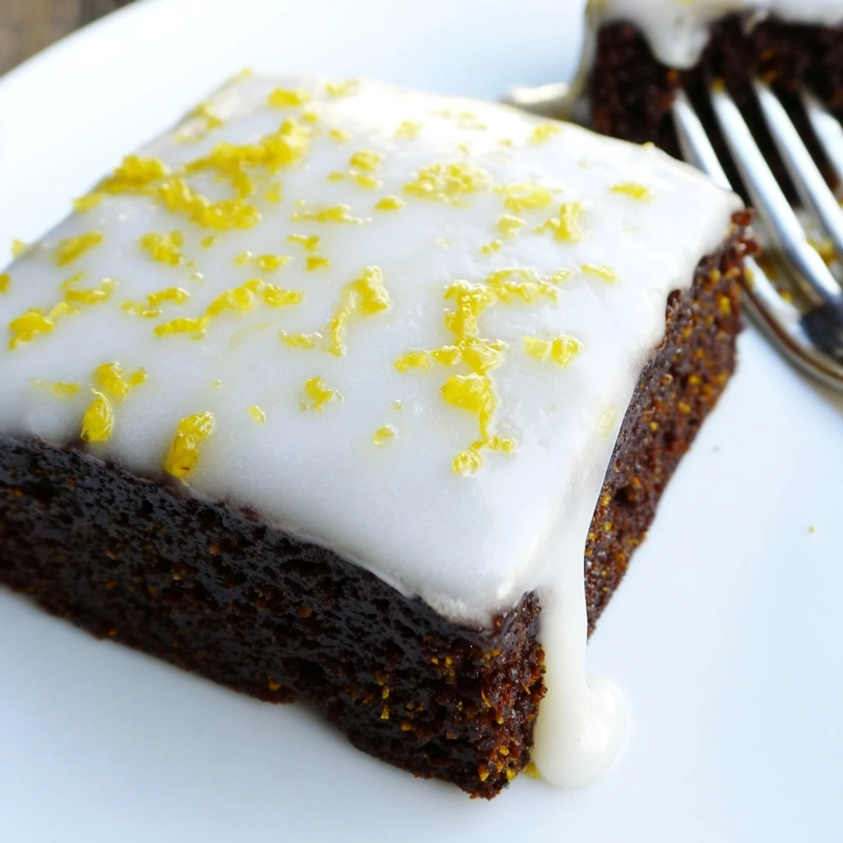 Rich fudgy lemon zest buttery brownies cut into squares with powdered sugar dusting and lemon peel twists