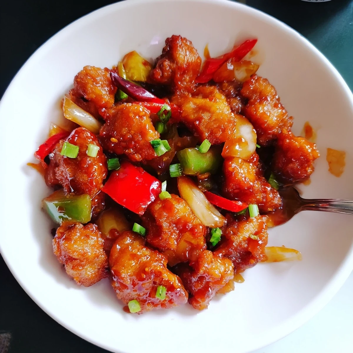 Saucy Flavorful Chilli Chicken Indo Chinese steaming in wok, garnished with scallions  