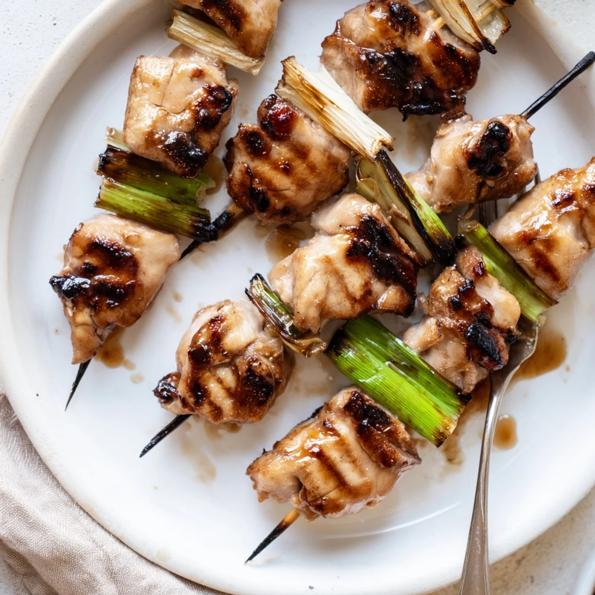Glazed skewers steaming on plate, Japanese Chicken Yakitori Recipe with scallions