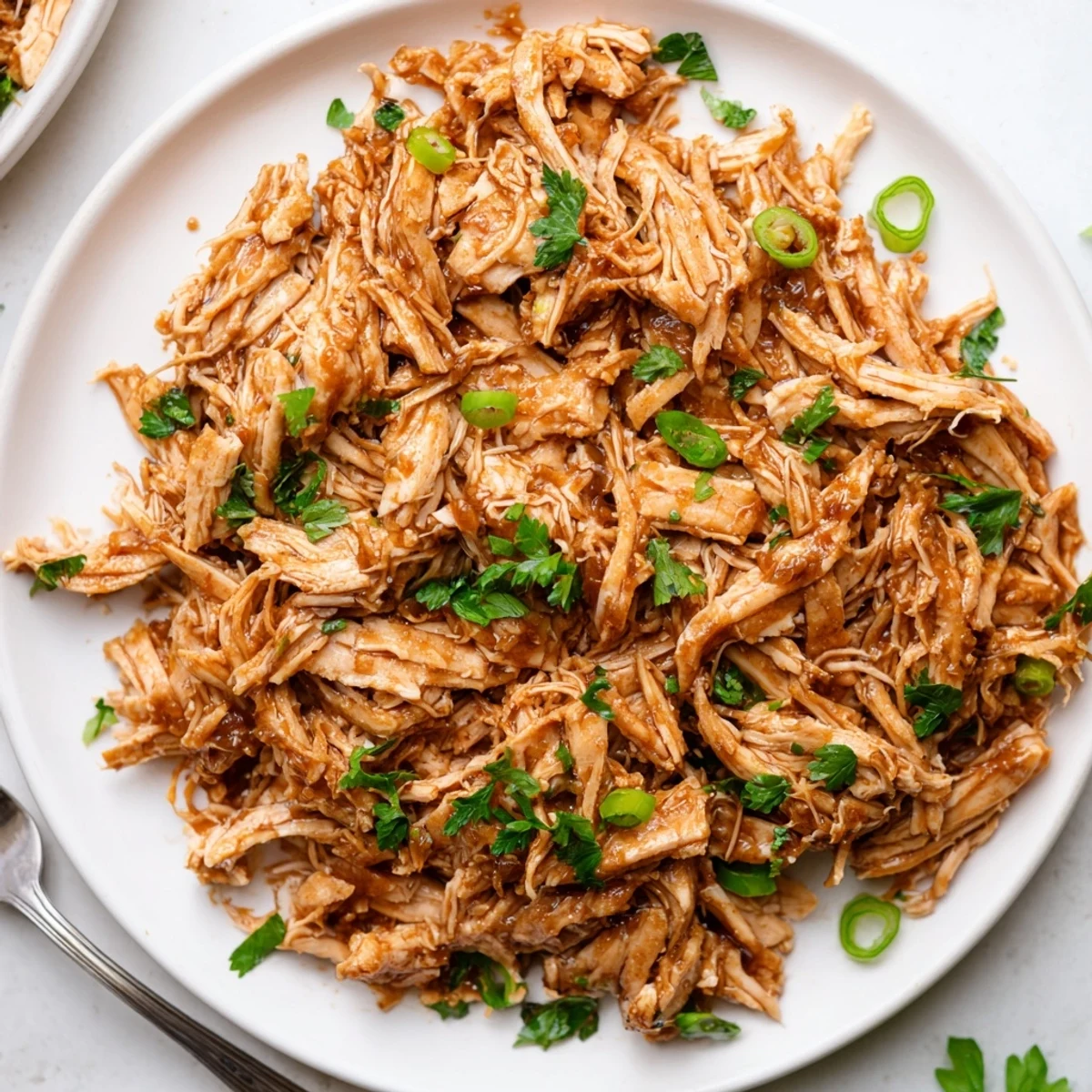 Tender and shredding easily, Slow Cooker Brown Sugar Garlic Chicken topped with green onions.