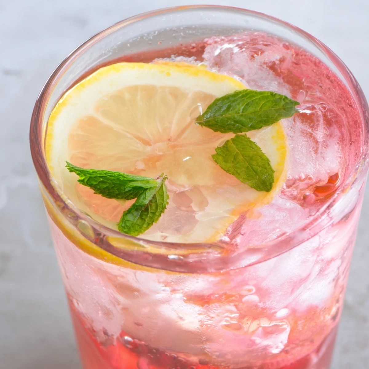 Sparkling honey lemon pink soda poured over ice and garnished with lemon slices