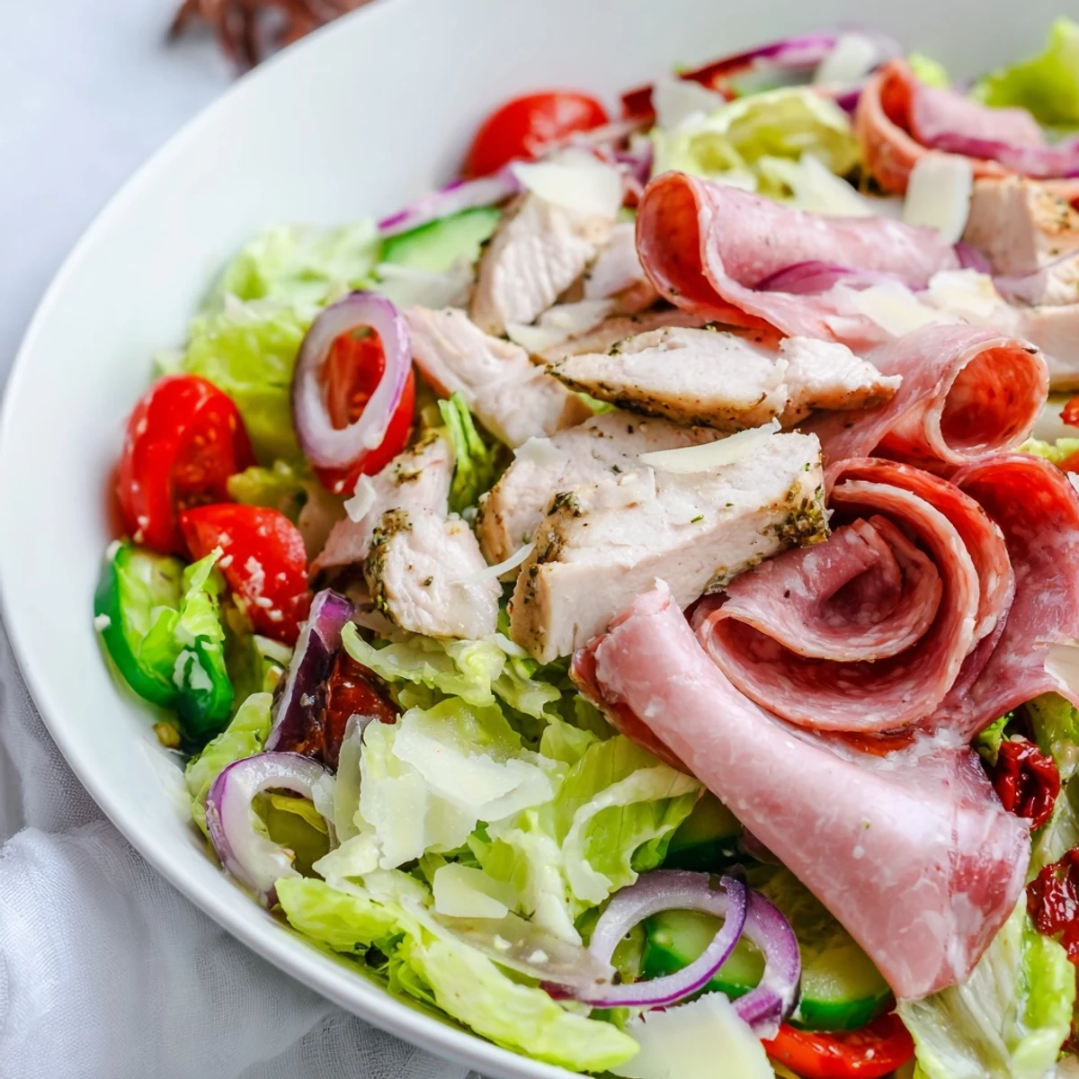 Italian Grinder Chicken Salad layered with crisp romaine, juicy tomatoes, sliced salami, and tangy vinaigrette