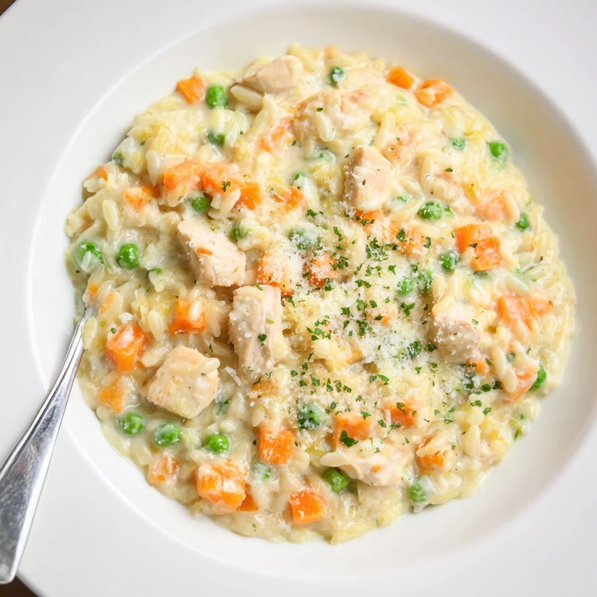Steaming bowl of creamy chicken pot pie orzo loaded with tender vegetables and golden chicken