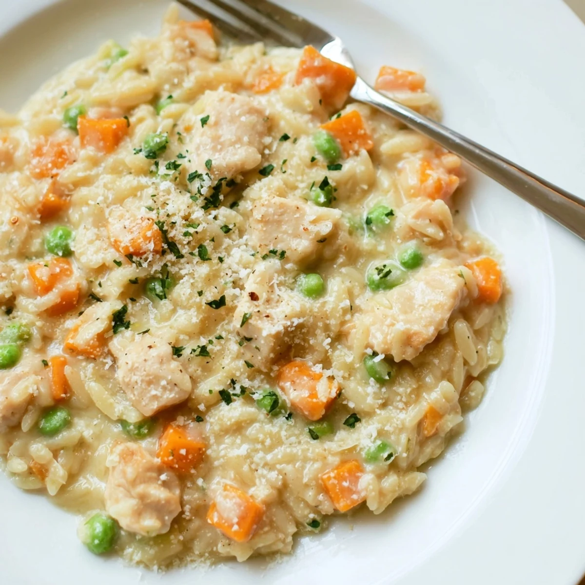 Creamy chicken pot pie orzo garnished with fresh parsley in a rustic white bowl