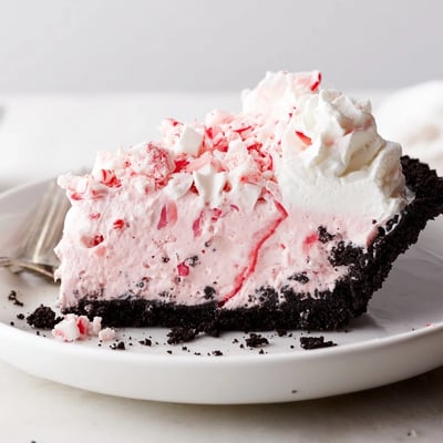 A slice of Candy Cane Pie topped with whipped cream and candy cane pieces