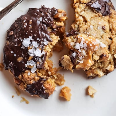 A stack of Chocolate Dipped Toffee Cookies on a plate, ready with milk